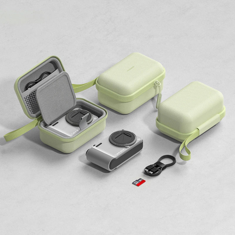 A pale mint green protective camera case set shown on a light gray surface, with one case open to reveal a gray interior and strap, one case closed, a silver action camera, a black USB-C cable, and a small memory card.