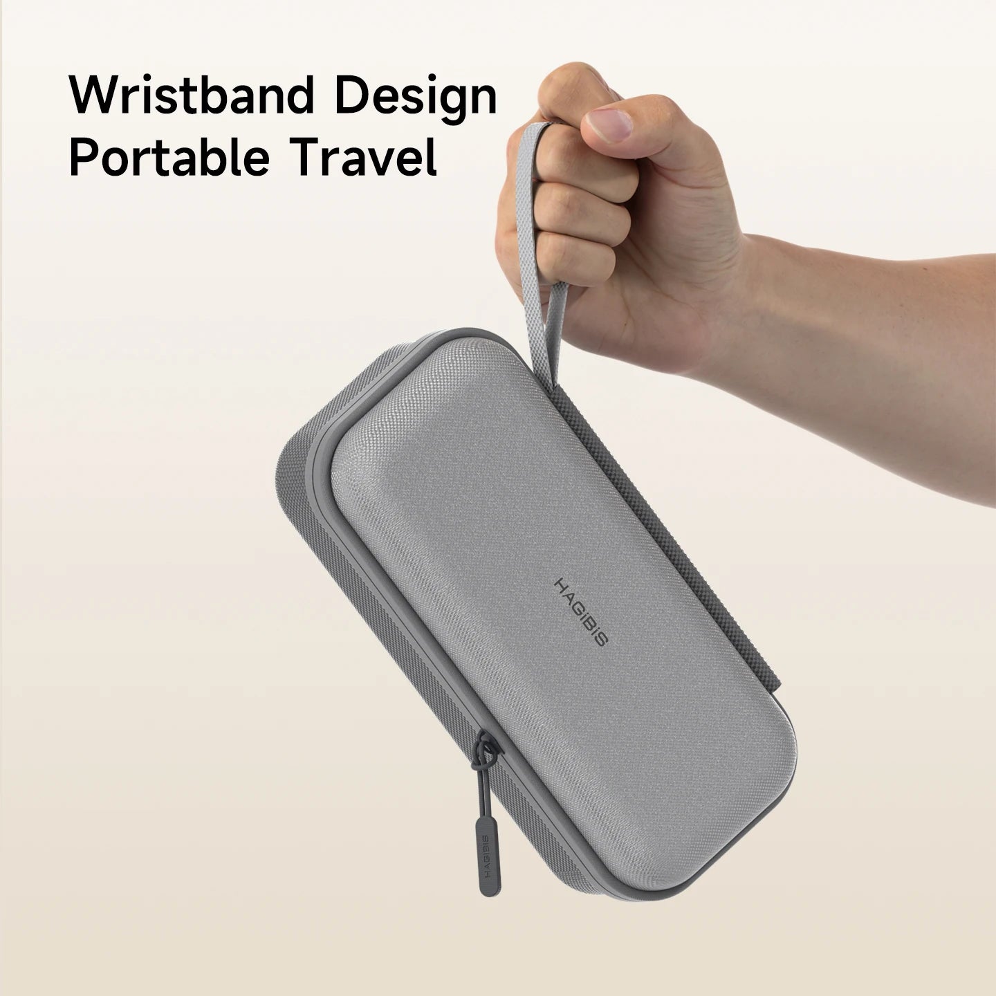 Gray travel case with wrist strap held by a hand on a beige background