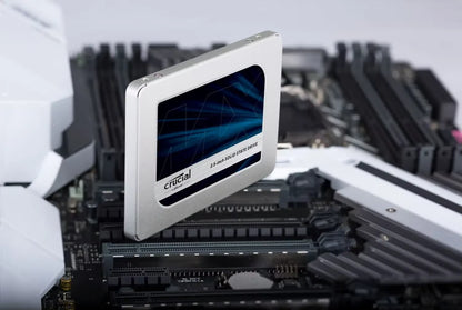 A Crucial 2.5-inch SSD shown floating above a motherboard, highlighting its silver metal casing and blue graphic display window.